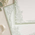 Gros plan du bloc-notes B5 Thorn Rose avec bordure de roses vert sauge et pages lignées