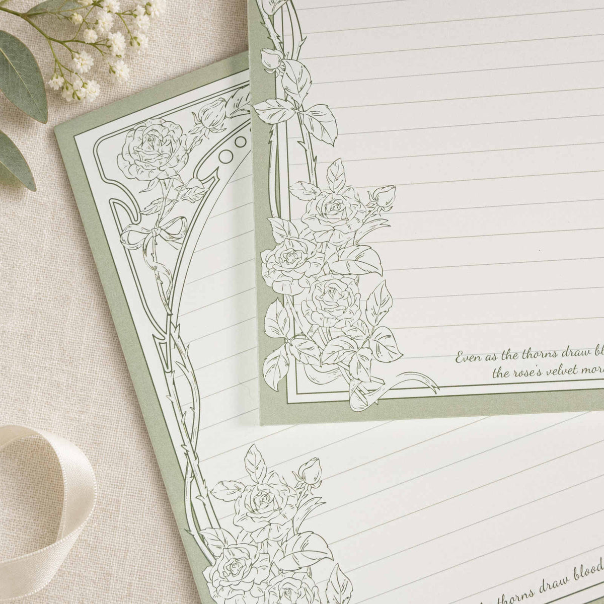 Gros plan du bloc-notes B5 Thorn Rose avec bordure de roses vert sauge et pages lignées